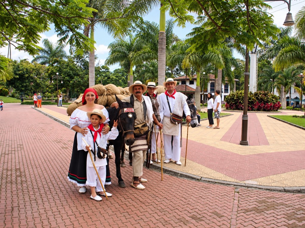 Alexandra y Danny vestidos de arrieros en la plaza, junto a mulas cargadas de café y arrieros del parque