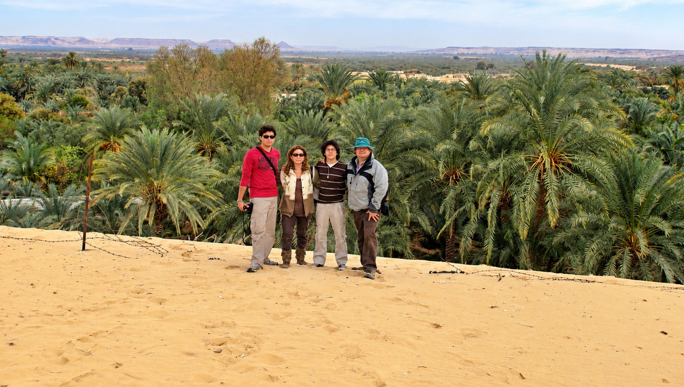 Juanes, Alexandra, Danny y Jairo sobre una duna, con el palmeral inmenso del Oasis de Bahariya al fondo
